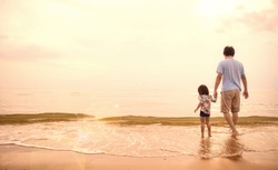 Asian father and little girl walk hold hand along the sand beach at the sunset, Dad playing with daughter the beach. Together travel love family Father’s day holiday concept