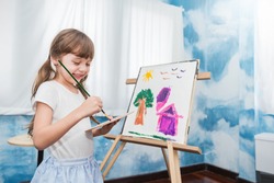 Portrait of little caucasian girl painting with copy space watercolor in her art kindergarten classroom. Young creative gifted artist home school education learning by doing back to school concept