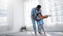 Portrait of happy African American father, teacher and little black girl daughter playing violins. Family leisure time doing hobby with music instrument. Love together fatherhood, Father's Day concept