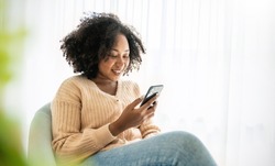 African American black woman smile use tablet smartphone in blue winter sweater work home, Portrait beauty  girl hygge relax on chair. Technology people connection digital online social media market