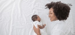 Closeup portrait of beautiful young African American mother day girl kiss healthy newborn baby sleep in bed flat lay copy space. Healthcare medical love black woman lifestyle mother's day, top view