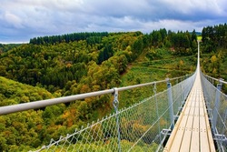Geierlay- cableway suspension bridge in Germany. Hunsrück region in Rhineland-Palatinate. Picturesque bridge over the valley of the Mersdorf stream. Windy and cold autumn day