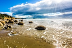 Moeraki Boulders is the group of large spherical boulders. The South Island of New Zealand. Popular tourist attraction. Low tide in the Pacific ocean. The concept of exotic and ecological tourism