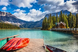 Brilliant red kayaks dry upside down. Emerald Lake in Canadian Rockies. Concept of active vacation and tourism