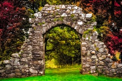 Old stone entrance wall in the garden with beautiful colorful foliage