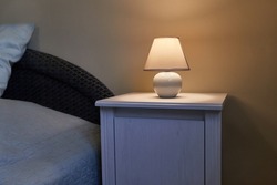 Small lamp glowing in bedroom next to the bed at night