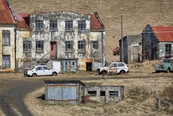 Abandoned farm house ruins in Iceland with rusty vehicles around
