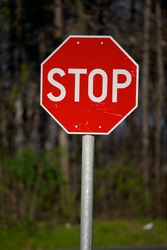 Stop sign closeup with woods in the background