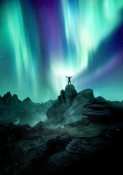 The Northern Lights dance across the night sky as a silhouetted man reaches up towards it. Photo composite.