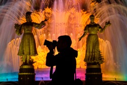 Photographer on the background of fountains at VDNH at night