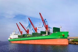 A ship with red and green stripes in the port of Riga for loading and unloading port cranes
