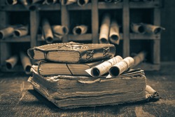 Old books and antique scrolls in library on wooden table