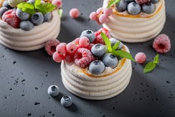 Homemade mini Pavlova dessert with whipped cream and frozen fruit. Dessert made of meringue with frozen berries and cream.