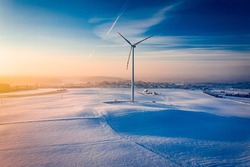Wind turbine on snowy field in winter. Alternative energy. Aerial view of nature in Poland, Europe
