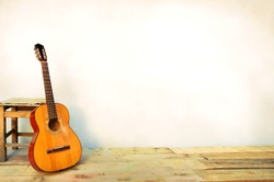 Spanish guitar propped in front of a white wall as background 