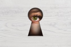 Abstract keyhole opening with eye on wooden wall background. Access and vision concept