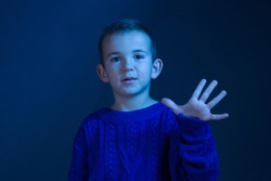 Studio portrait of a brunette Boy who counts on his fingers, shows five fivefinger