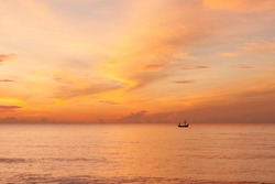 A beautiful morning sky with a fisherman on a boat in the sea, a beautiful orange sky with cloud reflection on the sea. Taken at Hua hin beach, Prachuabkhirikhan, Thailand.