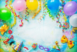 Balloons, present or gift box, confetti, candy, bow tie, sunglasses and streamers on colorful background with copy space. Top view. Birthday, carnival or party background