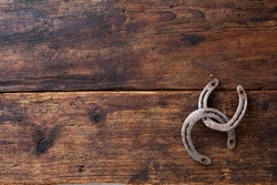 Two old rusty horseshoes on vintage wooden board