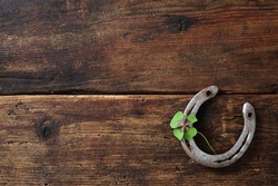 Old horse shoe with clover leaf on rustic wooden background