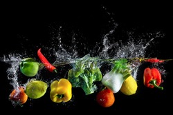 Vegetables splash in water on black background