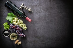 Bottle of wine, wineglasses, grapes and corks on dark background