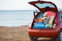 Suitcases and bags in trunk of car ready to depart for holidays. Moving boxes and suitcases in trunk of car, outdoors. trip, travel, sea. car on the beach with sea on background