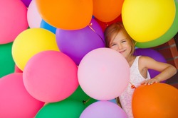 Little girl playing with balloons. Portrait of little girl playing with air balloons. Happy little girl holding colorful balloons.Smiling kid. happiness