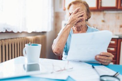 Elderly woman looking at her utility bills and paperwork