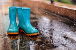 Green boots in rainy season. Boot in the rain. Green boot in the rain. Boots plyaing in the puddle.