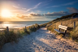 evening sunshine over bench and path to sea beach, Holland