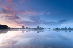 sunrise sky reflected in river during misty morning