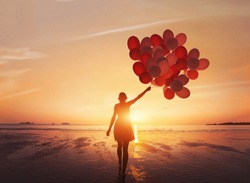 follow your dream, inspiration concept, silhouette of woman with colorful balloons on the beach