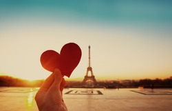 beautiful vintage card from Paris, Eiffel tower and hand with paper heart at sunrise