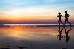 two runners on the beach, silhouette of people jogging at sunset, healthy lifestyle background with copyspace