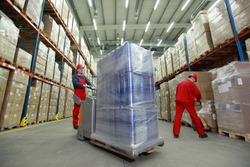 Warehousing -  Two workers in uniforms and safety helmets working in storehouse