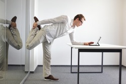 leg exercise durrng office work - standing man reading at tablet in his office