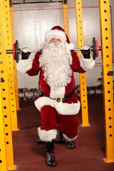 Santa Claus lifting weights in gym - physical condition training before Christmas 