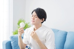 Asian man using the portable fan at home