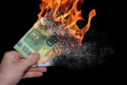 three burning euro bank notes held in one hand decomposes and dissolves due to inflation with black background