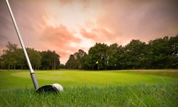chipping a golf ball onto the green with golf club at sunset with copy space