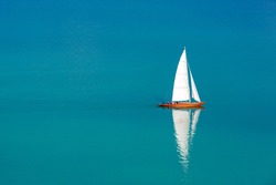 Perfect sailing background. Sailboat white sail and brown wooden boat in blue sea. Amazing recreational in nature concept design. Summer water sport, adventure outdoors