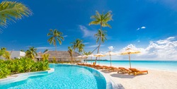 Panoramic holiday landscape. Luxurious beach resort hotel swimming pool and beach chairs or loungers under umbrellas with palm trees, blue sunny sky. Summer island seaside, travel vacation background