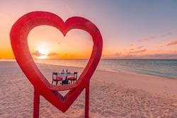 Honeymoon couples dinner at private luxury romantic dinner on tropical beach in Maldives. Seaside sea view, amazing island shore with red heart shape table chairs. Romantic love destination dining