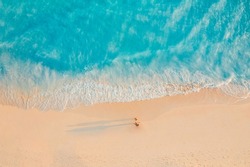 Aerial view of amazing beach with couple walking in sunset light close to turquoise sea. Top view of summer beach landscape, romantic inspirational couple vacation, romantic holiday. Freedom travel
