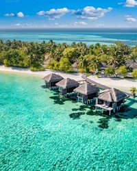 Perfect aerial landscape, luxury tropical resort with water villas. Beautiful island beach, palm trees, sunny sky. Amazing bird eyes view in Maldives, paradise coast. Exotic tourism, relax nature sea