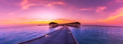 Amazing sunset panorama at Maldives. Luxury resort villas seascape with soft led lights under colorful sky.