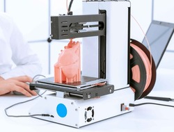 young woman student prints a model of the anatomical human heart on a 3D printer