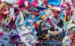 The background of many rag pieces of colorful fabrics which have been left from the sewing and repairing of the clothes by an elderly Thai woman for a long time.